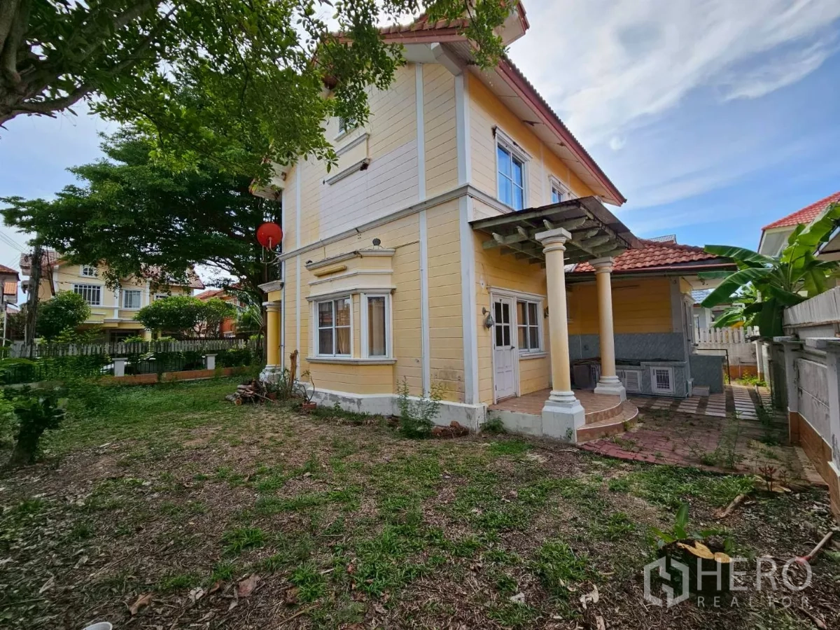 Detached House for rent or sale in Bang Lamung, Chon Buri - Rear and side yard with mature trees and a covered porch supported by pillars.