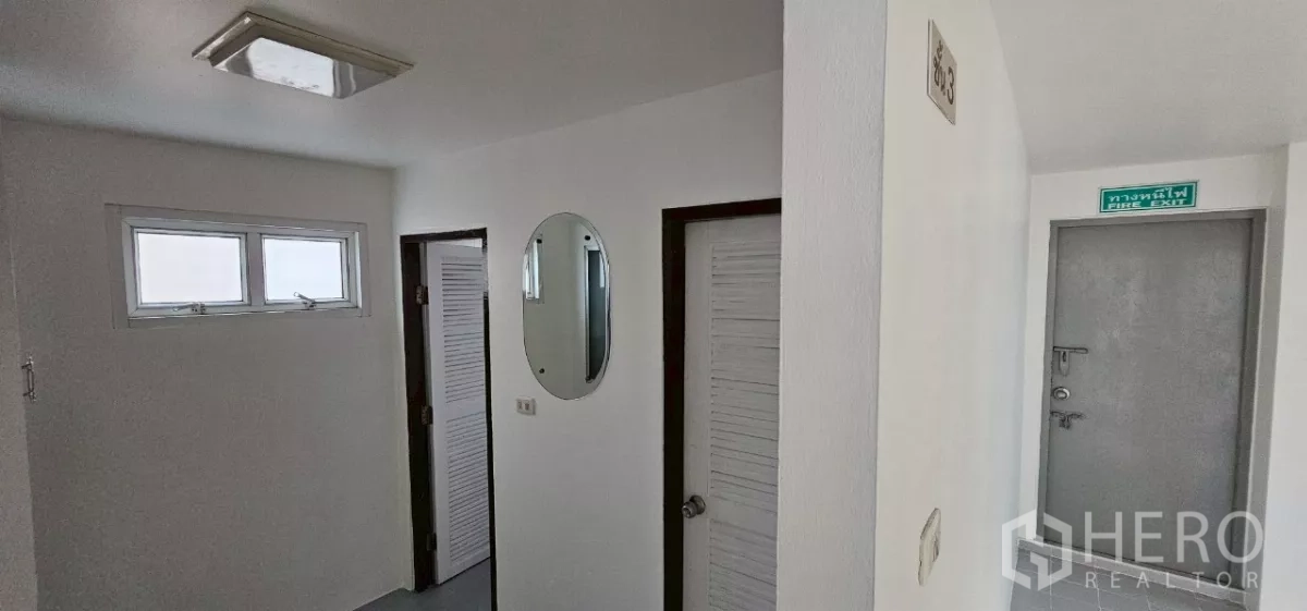 办公空间 出租在Bueng Kum, Bangkok - 走廊展示多扇洗手间门与明显的消防出口。