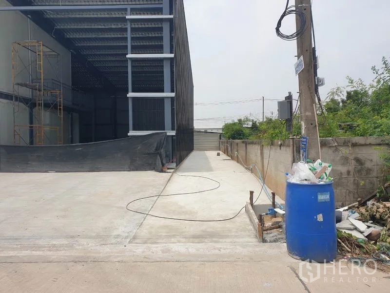 Warehouse for rent in Lam Luk Ka, Pathum Thani - Side driveway beside the warehouse leading to a rear gate, suitable for truck access.