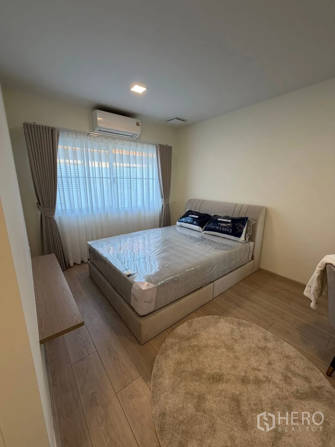 Detached House for rent in Bang Phli, Samut Prakan - Secondary bedroom with upholstered bed, window drapes, AC and round rug.