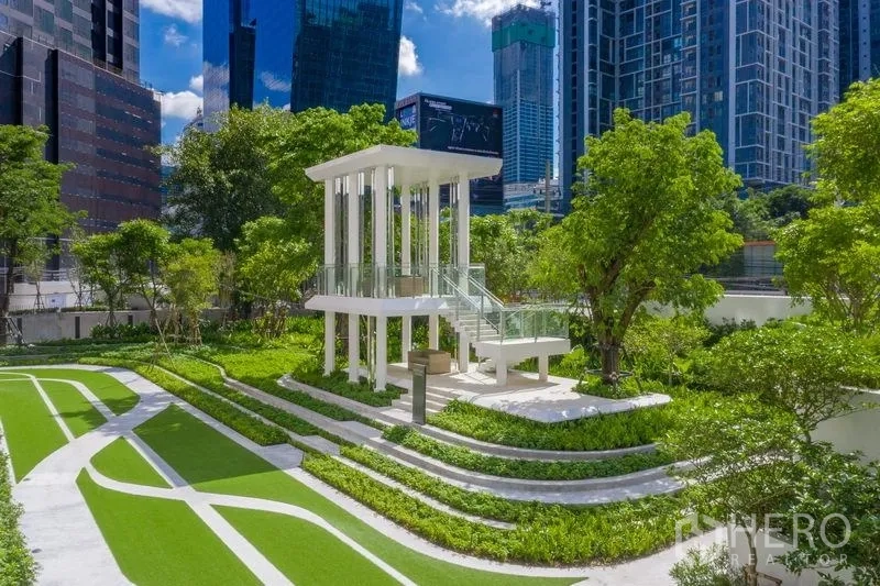 公寓 出售在Ratchathewi, Bangkok - 园林绿地配白色凉亭与步道，周围高楼林立。