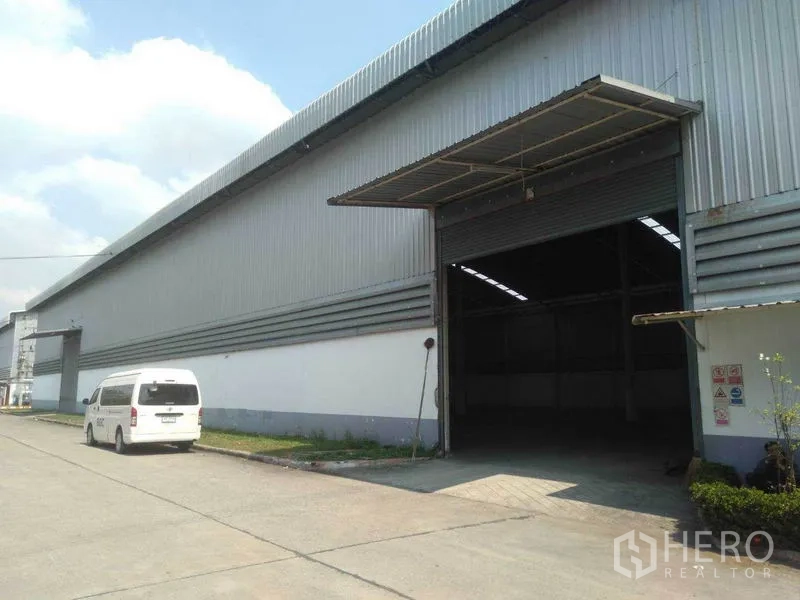 工厂 出租在Phra Nakhon Si Ayutthaya - 工厂外立面，大型卷闸入口及可通行卡车的车道。