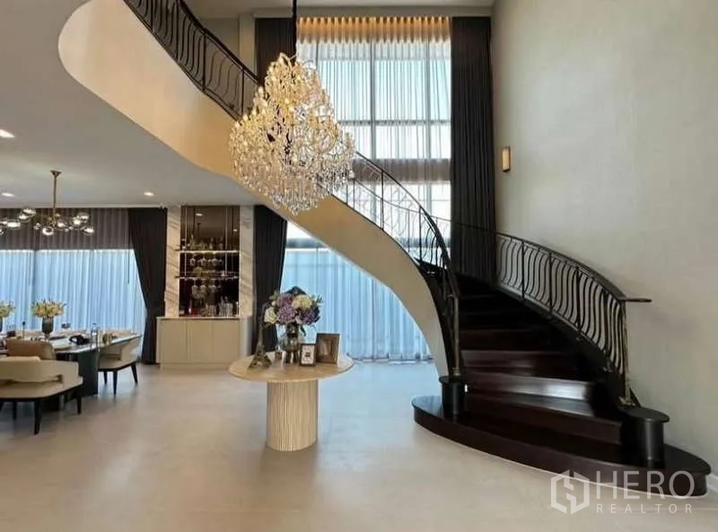 独立式住宅 出租在Lat Krabang, Bangkok - 迎宾大堂，旋转楼梯、水晶吊灯与餐区。