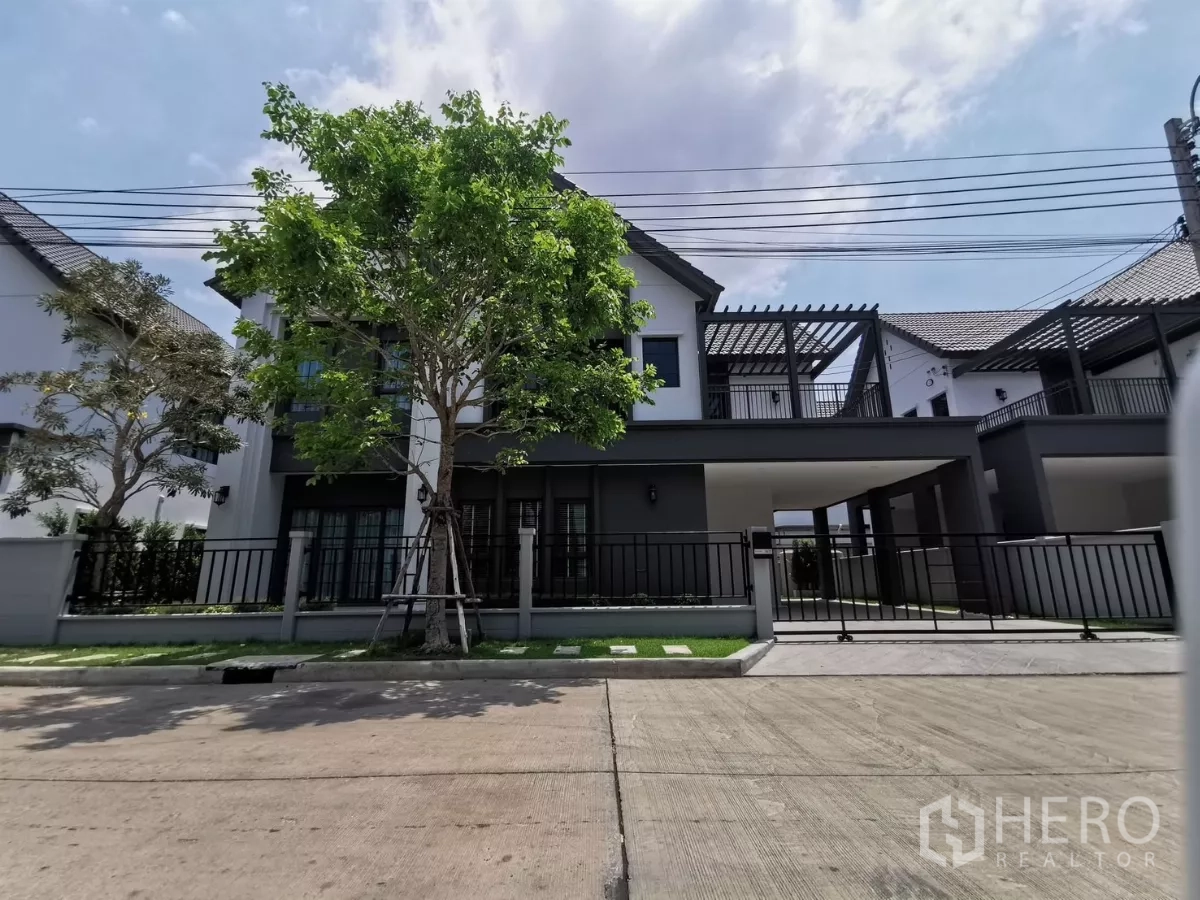Detached House for rent in Bang Phli, Samut Prakan - Modern two-storey detached house with front gate, carport and tree-lined frontage in a gated community of Bang Phli.