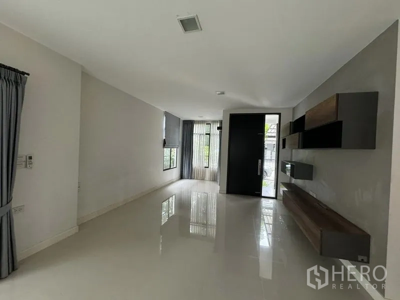 Detached House for rent in Samut Prakan - Open-plan living area with glossy tiles, built-in wall shelves and large door.
