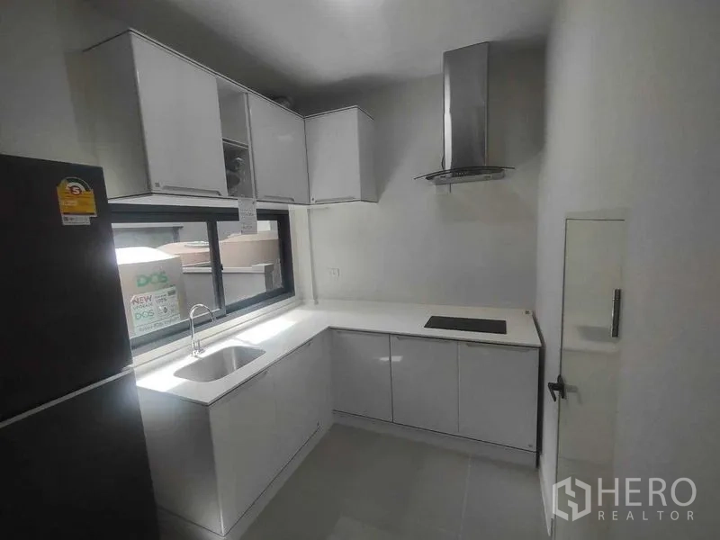 独立式住宅 出租在Khan Na Yao, Bangkok - 白色L型厨房，带水槽、窗户、灶台与不锈钢烟机。