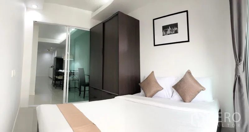 Condominium for rent or sale in Khlong Toei, Bangkok - Bedroom with sliding glass door, dark wardrobe, and outlook to the dining and kitchen area.