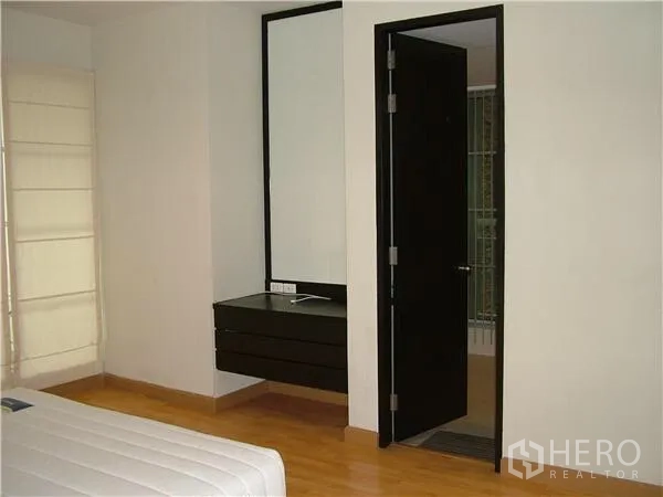 Condominium for rent in Khlong Toei, Bangkok - Bedroom corner with built-in vanity, large mirror, and door to an ensuite bathroom.