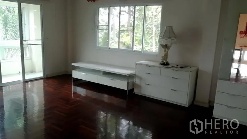 Detached House for rent in Lat Krabang, Bangkok - Upstairs bedroom with polished wooden floors, white cabinets, balcony access, and leafy views.