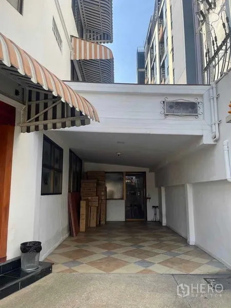 店屋 出租在Phaya Thai, Bangkok - 商铺入口及有顶停车区，棋盘格地砖与条纹遮阳篷。