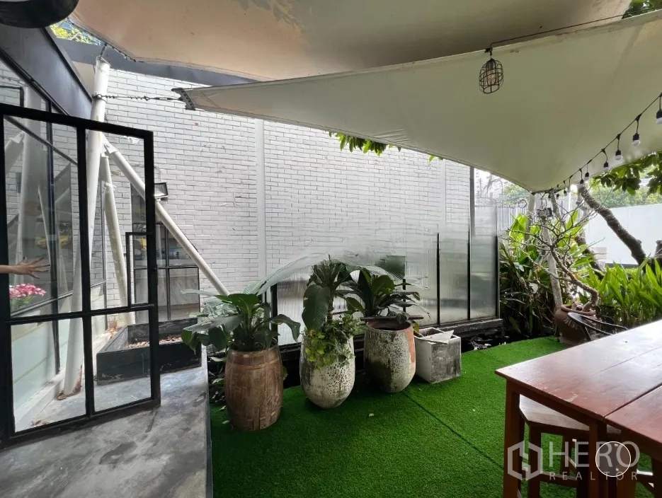 Retail Space for rent in Pathum Wan, Bangkok - Shaded outdoor patio with artificial grass, potted plants and string lights beside the shop.