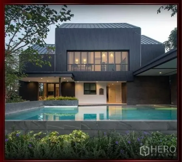 Detached House for sale in Khan Na Yao, Bangkok - Estate clubhouse with large outdoor swimming pool and landscaped deck at dusk.