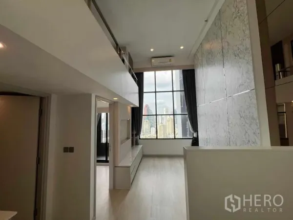 Condominium for sale in Sathon, Bangkok - Bright living room with mezzanine walkway and dramatic city-view window.