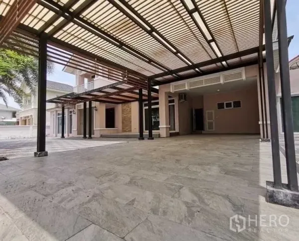 独立式住宅 出售在Lat Krabang, Bangkok - 现代木格栅顶的大面积铺砖车道与车棚。