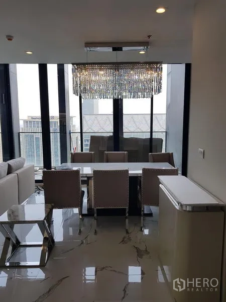 公寓 出租在Pathum Wan, Bangkok - 餐区在水晶吊灯下，面对通高窗与天际线