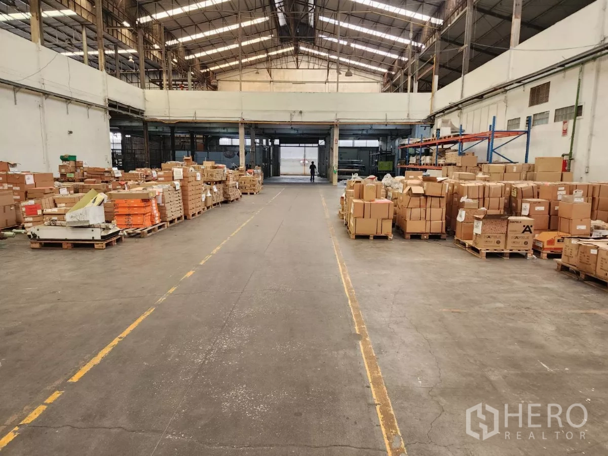 Factory for rent in Mueang Samut Sakhon, Samut Sakhon - Warehouse aisle with organized pallets of cartons and a high roof.