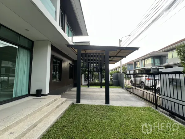 Detached House for rent in Bang Kapi, Bangkok - Front yard with grass, steps to sliding glass doors and a steel canopy.