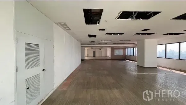 Office Space for rent or sale - Long floor plate with white walls, ceiling grid openings, and perimeter windows.