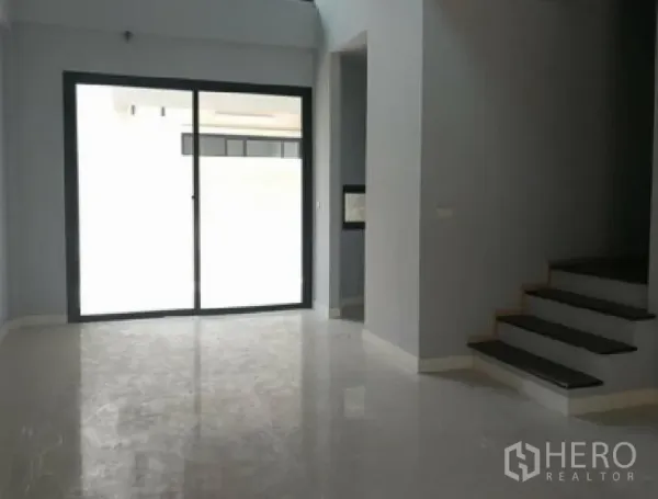 Townhouse for rent in Yan Nawa, Bangkok - Open-plan living area with polished floors, sliding glass doors to a terrace and a side staircase.