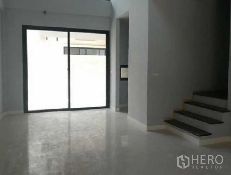 Townhouse for rent in Yan Nawa, Bangkok - Open-plan living area with polished floors, sliding glass doors to a terrace and a side staircase.