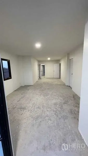 Townhouse for sale in Prawet, Bangkok - Long upper-floor room with multiple doors and windows and neutral walls.