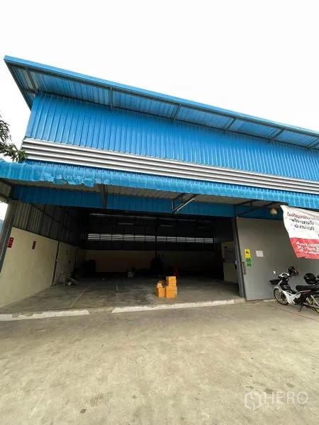 货栈 出租在Khlong Luang, Pathum Thani - 仓库正立面，大型滑动门与前方停车/卸货区