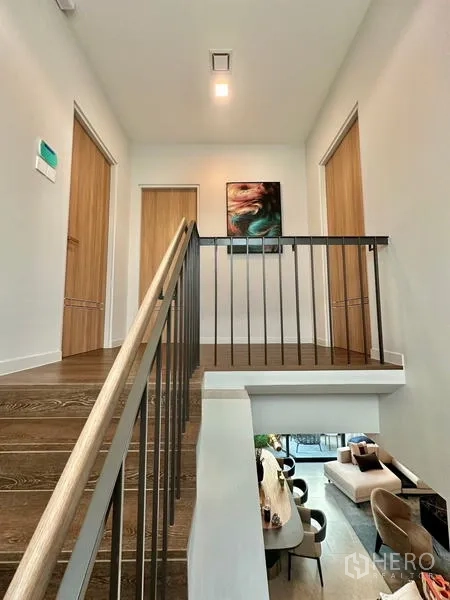 Detached House for rent in Samut Prakan - Upper landing and staircase with metal railing and artwork on the wall.