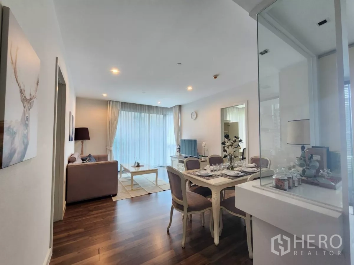 Condominium for rent in Phra Khanong, Bangkok - Bright open-plan living and dining room with hardwood floors, vintage table set, and floor-to-ceiling curtains.