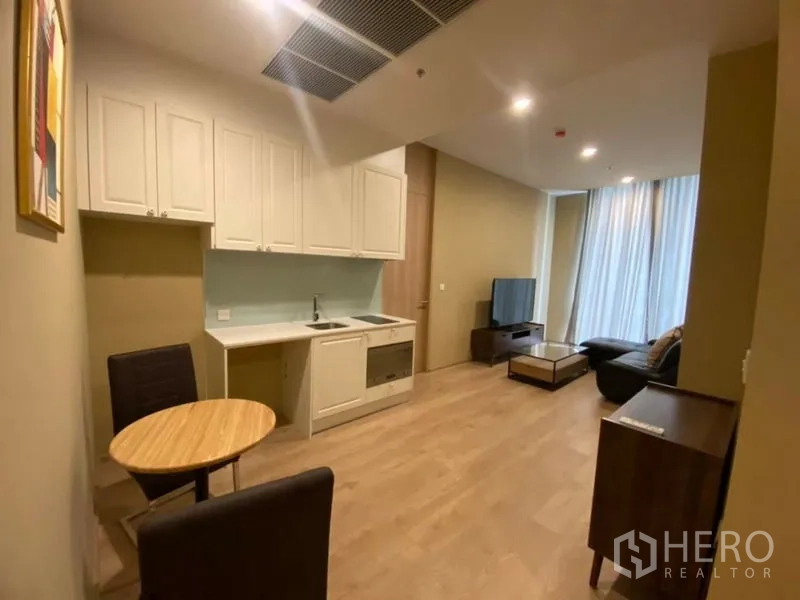 Condominium for rent in Watthana, Bangkok - Open-plan kitchen and lounge with dining nook, TV, sofa and large curtained windows.