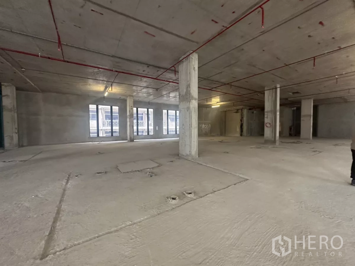 Retail Space for rent in Watthana, Bangkok - Shell‑and‑core retail space showing exposed sprinkler pipes, support pillars and multiple windows.