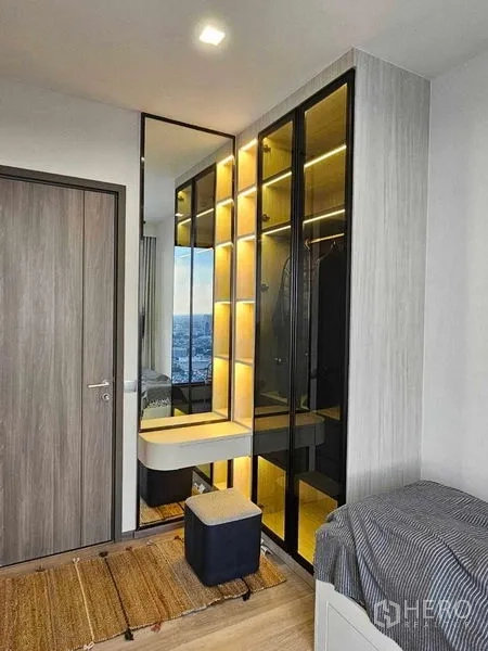 Condominium for rent in Bang Kho Laem, Bangkok - Guest bedroom corner with illuminated glass-door wardrobe and compact vanity.