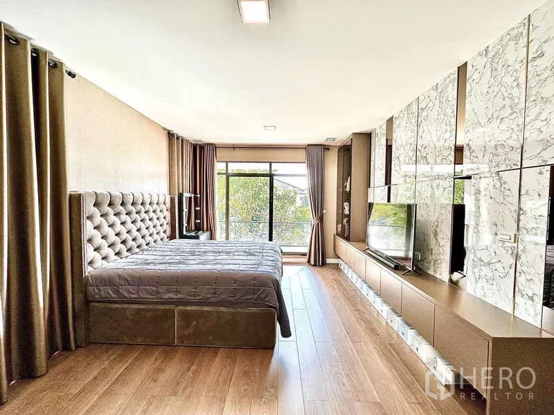 Detached House for sale in Bang Phli, Samut Prakan - Master bedroom with built-in marble TV wall, long cabinet and balcony doors.