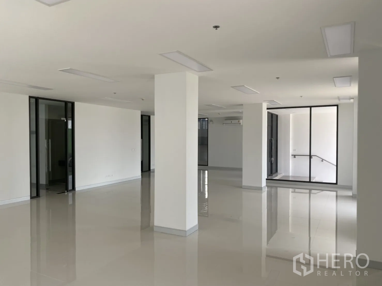 货栈 出租在Chachoengsao - 明亮的开放式办公室，白墙、玻璃隔断与瓷砖地面。