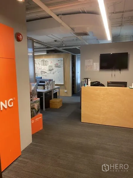 Office Space for rent in Khlong Toei, Bangkok - Reception area featuring a wooden counter, wall-mounted TV, and carpeted flooring.