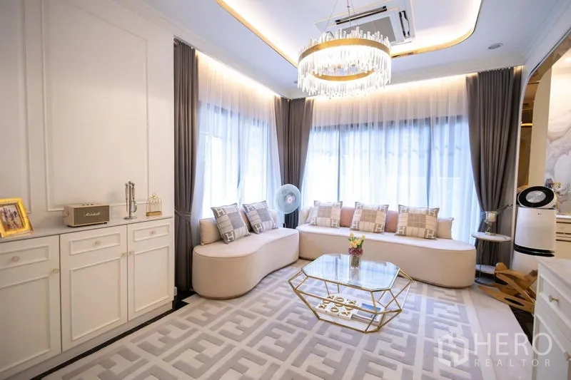 独立式住宅 出售在Pak Kret, Nonthaburi - 客厅另一视角，转角窗与吊灯一览。