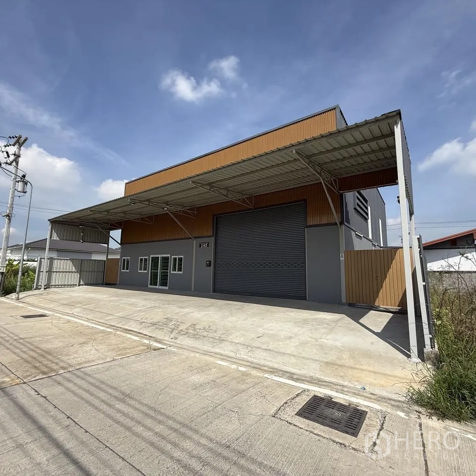 Warehouse for rent or sale in Khlong Luang, Pathum Thani - Front elevation featuring a covered loading bay, wide roller shutter and driveway.
