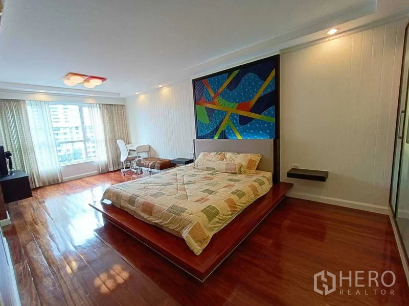 公寓 出租在Watthana, Bangkok - 宽敞主卧，平台床，大飘窗，实木地板与彩色墙面装饰画。