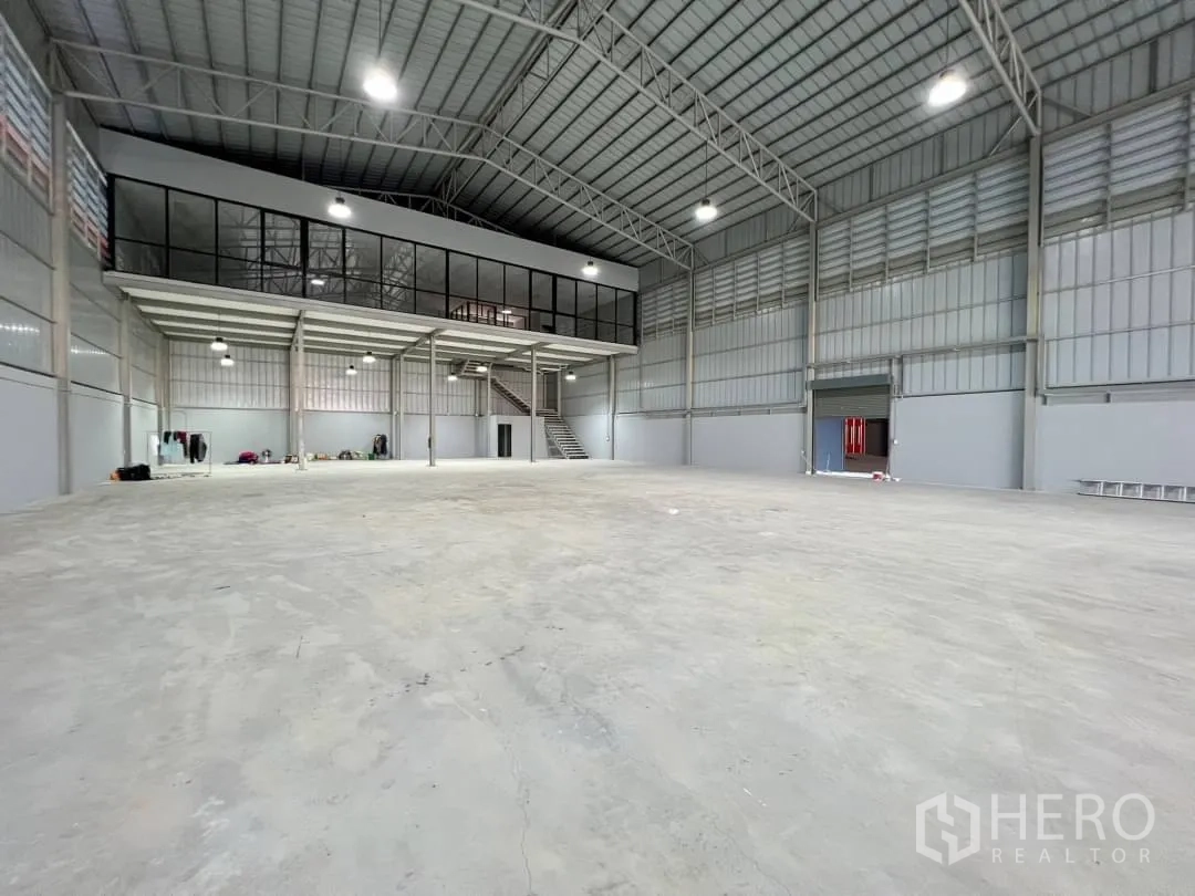 Warehouse for rent in Sai Mai, Bangkok - Expansive high-ceiling warehouse with glazed mezzanine office and wide roller door.