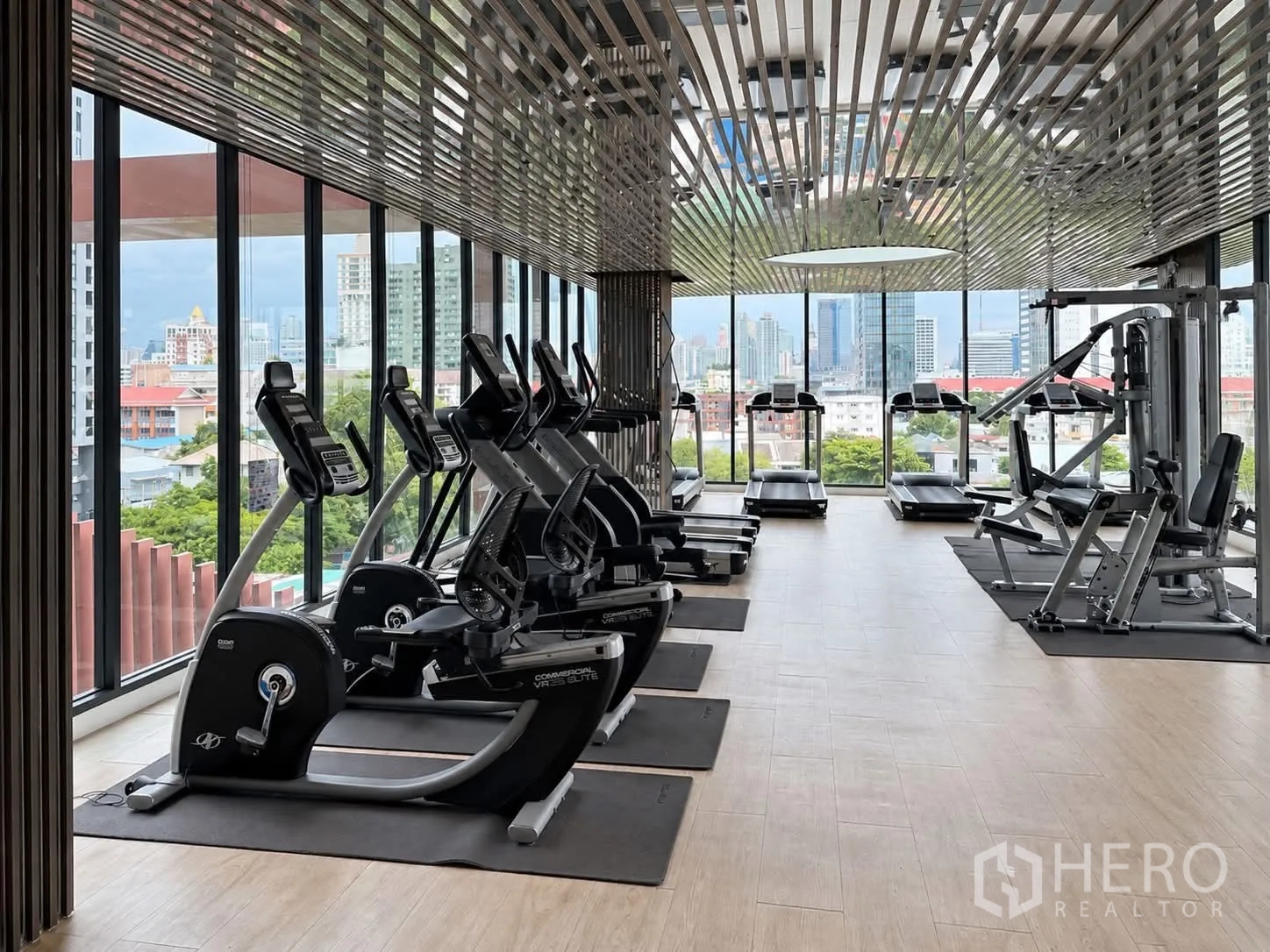 Condominium for rent in Watthana, Bangkok - Light-filled fitness center with treadmills, bikes, and weight machines facing city views.