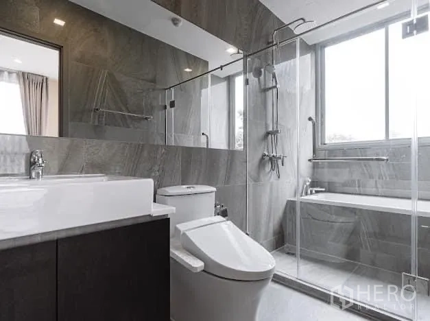 คอนโด ให้เช่าในWatthana, Bangkok - ห้องน้ำสมัยใหม่พร้อมฝักบัวกระจก อ่างอาบน้ำริมหน้าต่าง และผนังหินสีเทา