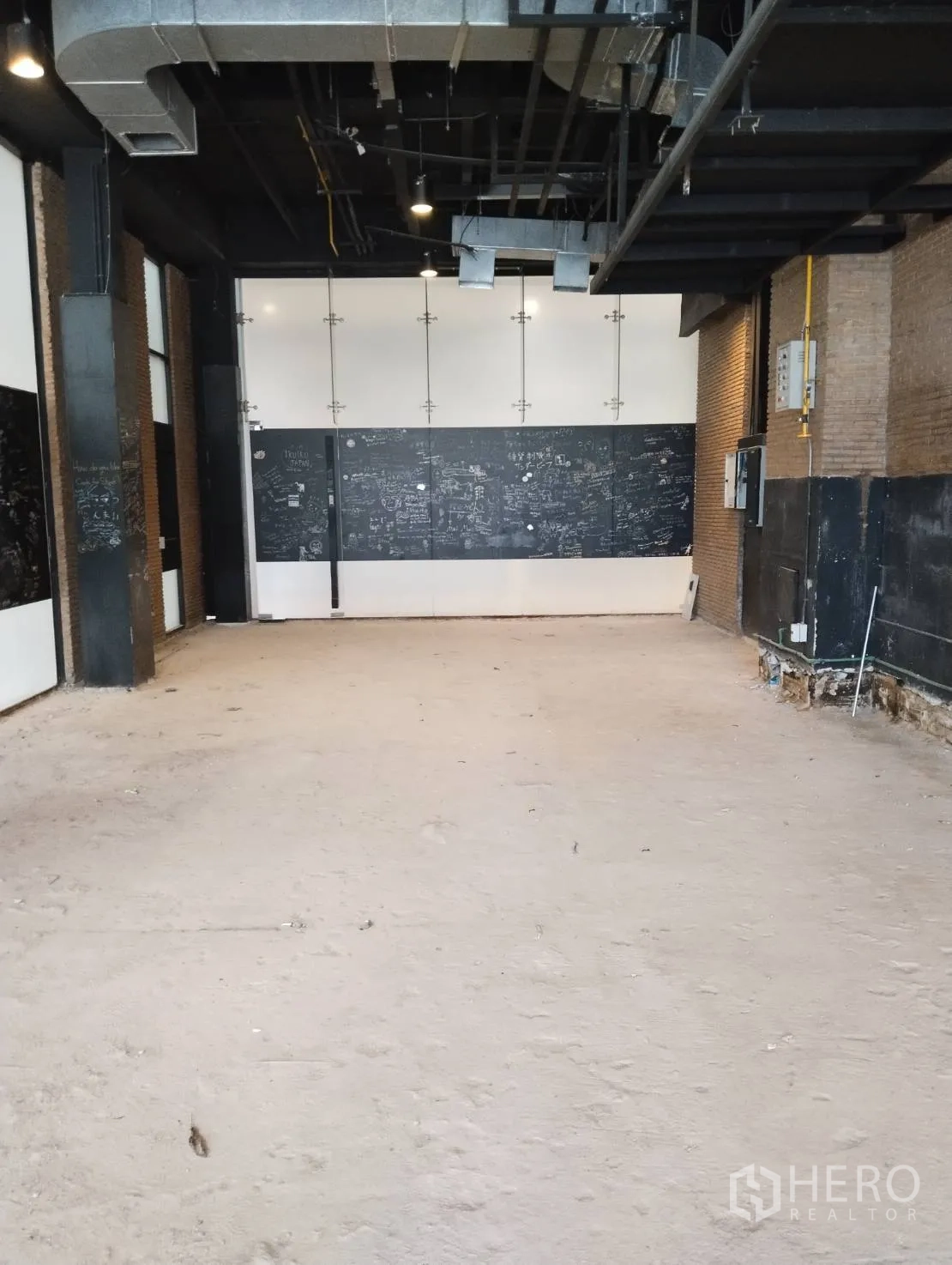 Retail Space for rent in Khlong Toei, Bangkok - Unfitted retail unit with high exposed ceiling, ductwork, brick accents and a bare concrete floor.