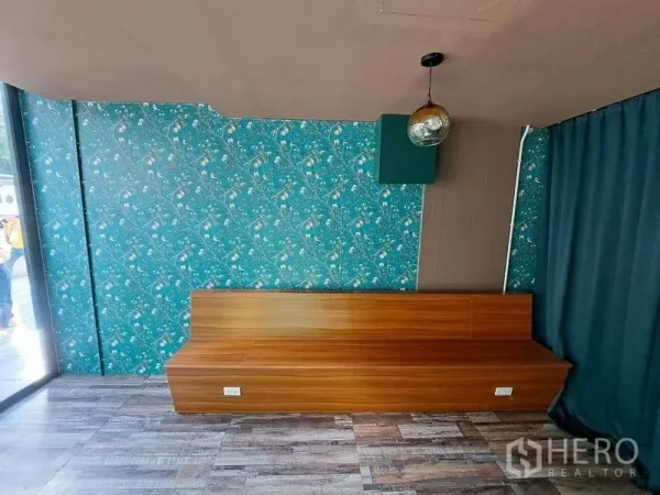 Retail Space for rent in Bang Rak, Bangkok - Seating nook with long wooden bench, teal floral feature wall, and wood-look flooring.