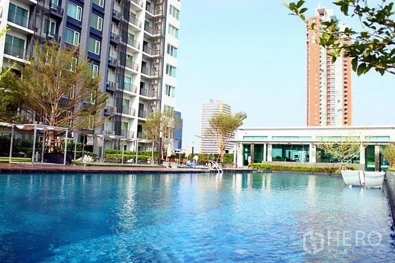 Condominium for rent in Khlong Toei, Bangkok - Large outdoor swimming pool with landscaped deck beside modern condominium buildings.