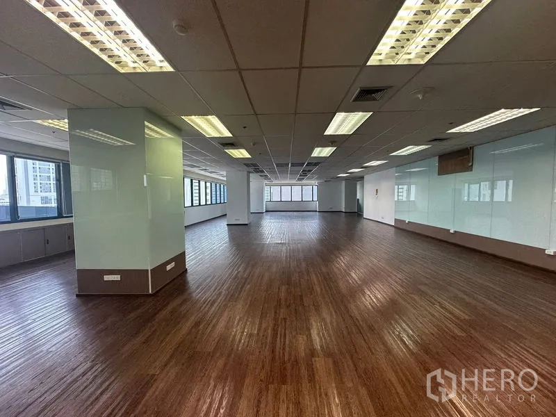 Office Space for rent in Bang Rak, Bangkok - Large open-plan office floor with wood flooring and rows of windows.