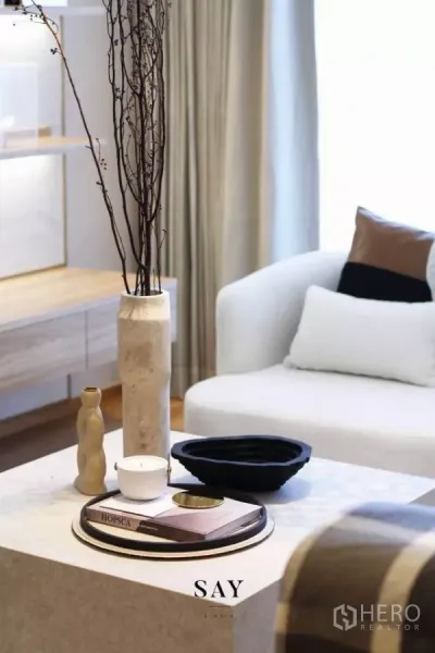 Condominium for rent or sale in Khlong Toei, Bangkok - Coffee table styling with tray, vases and branch arrangement beside an armchair and shelving.