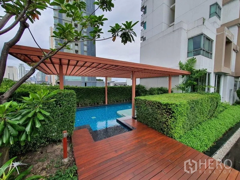 Condominium for sale - Quiet plunge pool with a wooden pergola and deck surrounded by manicured hedges.