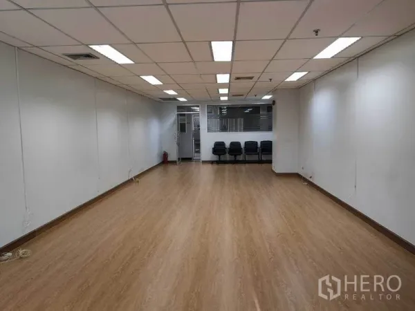 办公空间 出租在Watthana, Bangkok - 从内向外望向入口的宽敞办公室，吊顶空调、木地板及玻璃隔断旁座椅。
