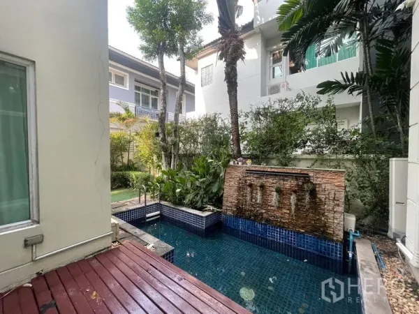 Detached House for rent or sale in Khan Na Yao, Bangkok - Private plunge pool with stone waterfall feature beside a landscaped garden and wooden deck.