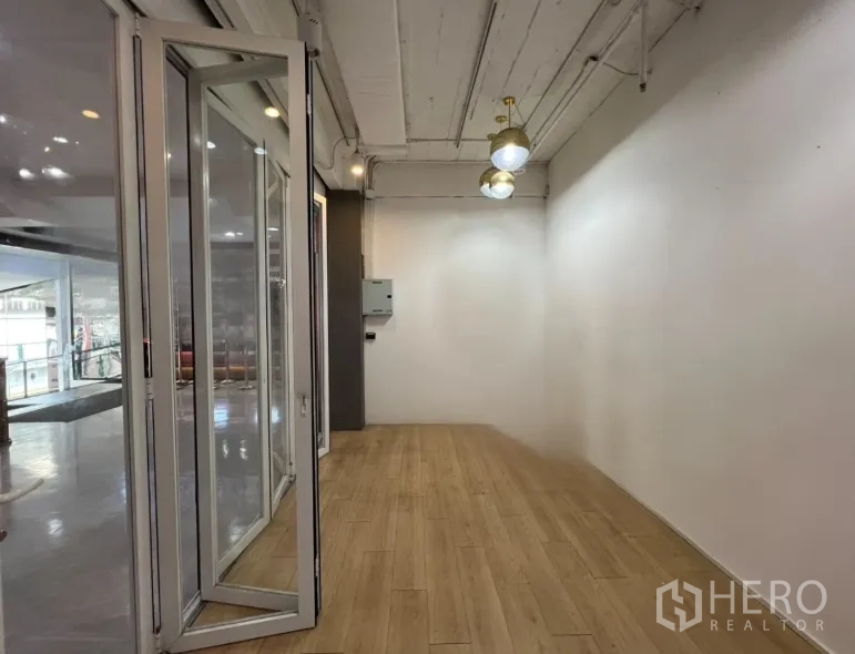 Retail Space for rent in Pathum Wan, Bangkok - Narrow interior of the retail space with wood floors, white walls, and pendant lighting overlooking the atrium.