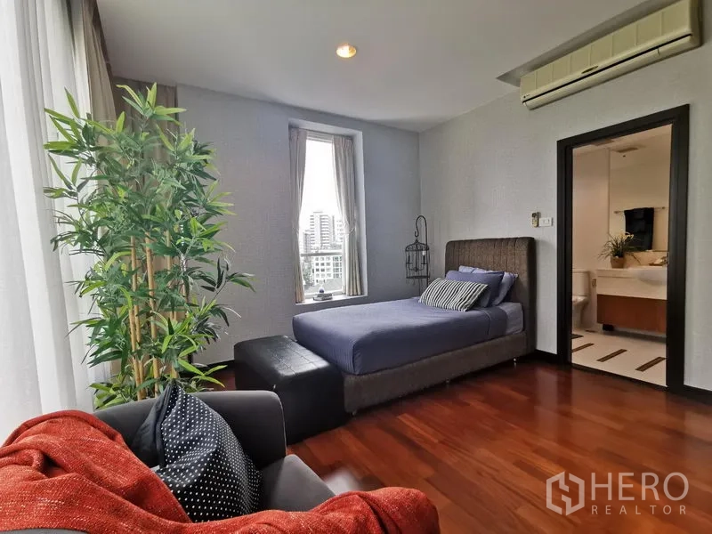 Condominium for rent or sale in Khlong Toei, Bangkok - Second bedroom with single bed, city-view windows, and access to an ensuite bathroom.